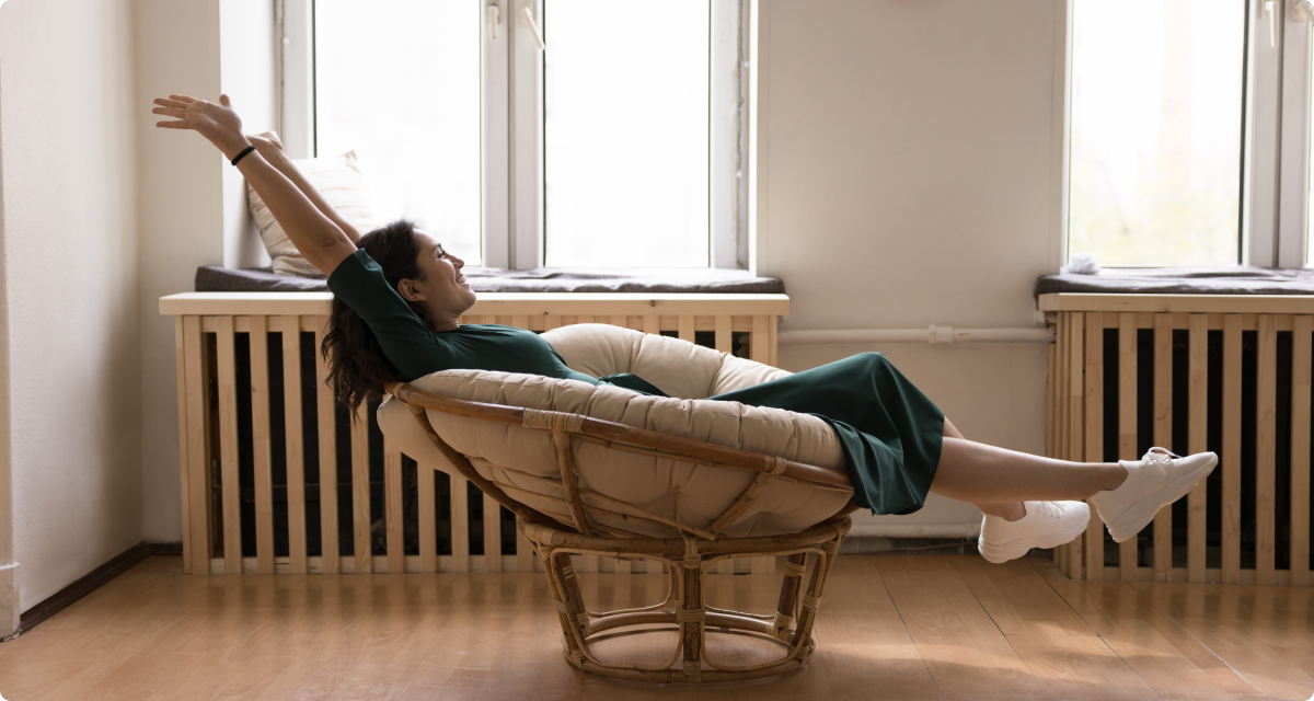 Woman in chair in front of window throwing arms in the air